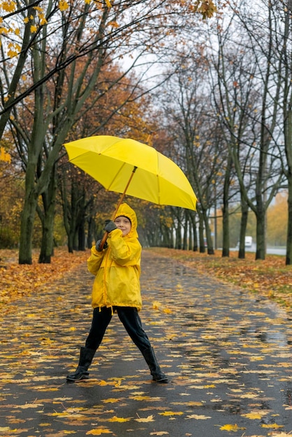 Little boy walks in the park and plays with an yellow umbrella Walking with child in rain Vertical frame