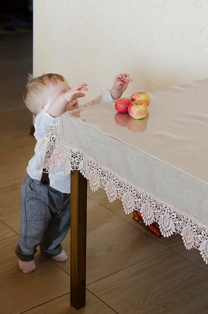 A little boy wants to steal an apple from the table