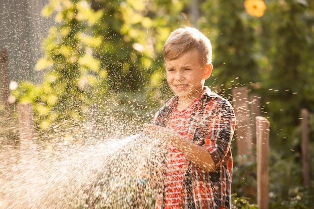 The little boy waters the plants making large splashes of water