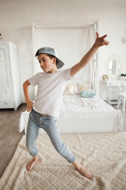 Photo little boy wearing cap and dancing in bedroom