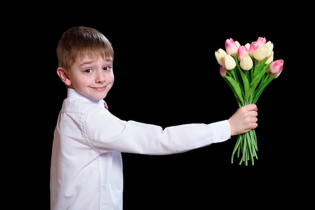 Little boy in white shirt gives a bouquet of tulips.