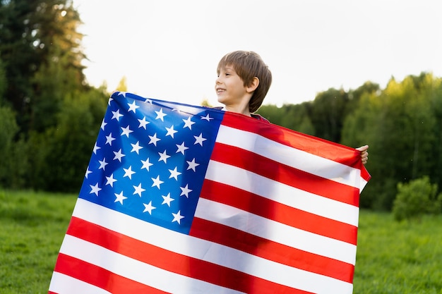 Little boy with the American flag in nature, the concept of patriotism and the  independence USA.