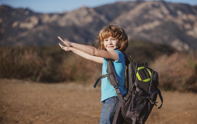 Little boy with backpack hiking in scenic mountains Kid local tourist goes on a local hike