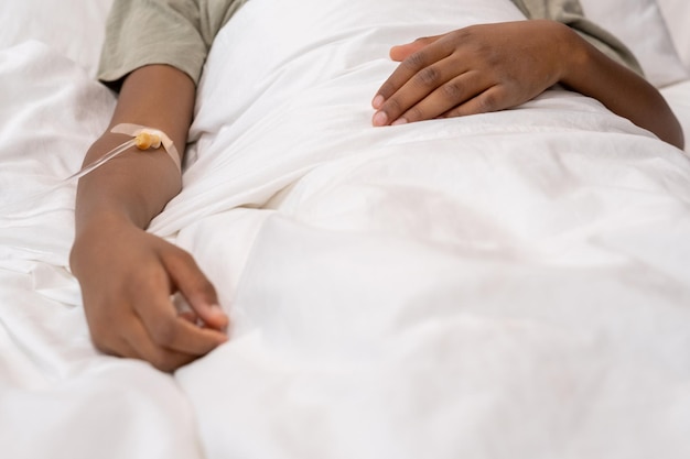 Little boy with dropper in his arm lying in bed