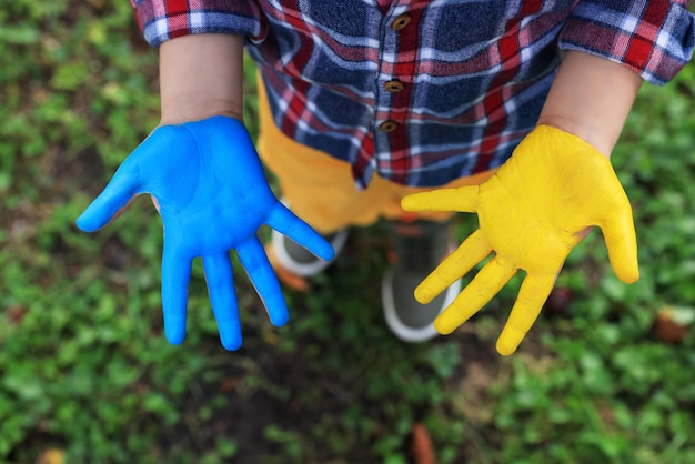 Little boy with hands painted in Ukrainian flag colors outdoors top view Love Ukraine concept