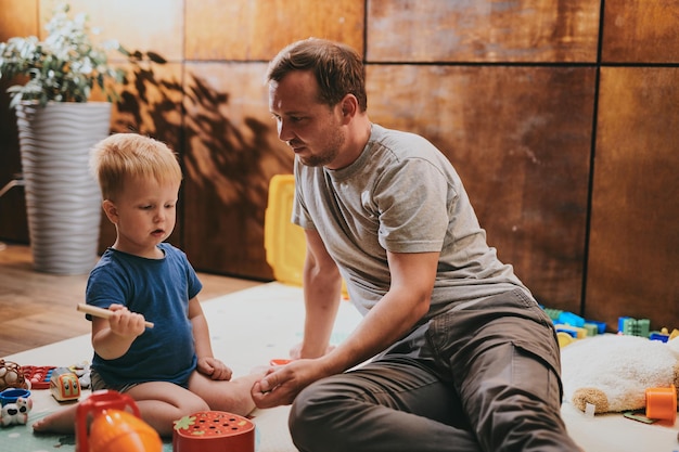 Photo little boy with his dad playing with toys at home happy father and son spending time together