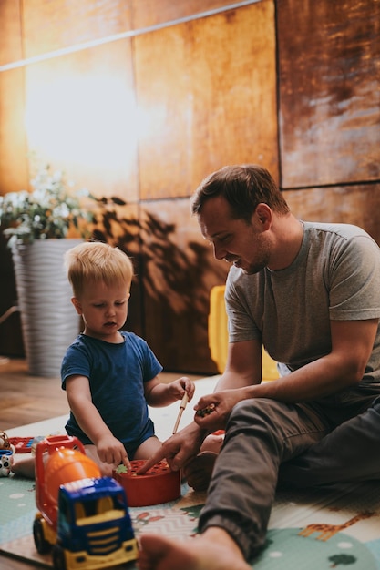 Photo little boy with his dad playing with toys at home happy father and son spending time together