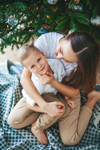 Little boy with his mother under the Christmas tree