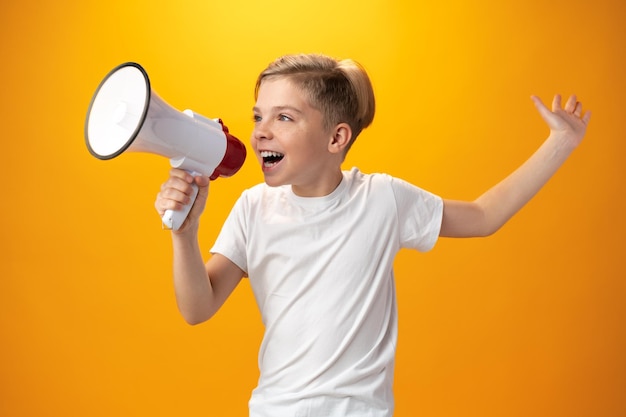 Little boy with megaphone on yellow background