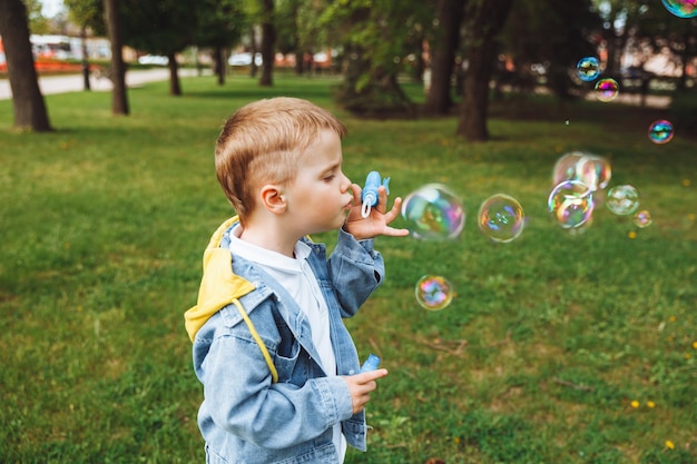 Little boy with soap bubbles in the park spring sunny day active games for kids