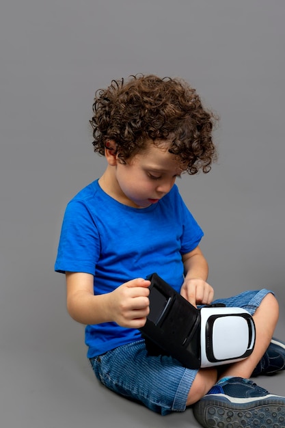 Little boy with virtual reality goggles in his hands looking curiously at how they work