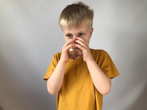 little boy in a yellow Tshirt drinks water