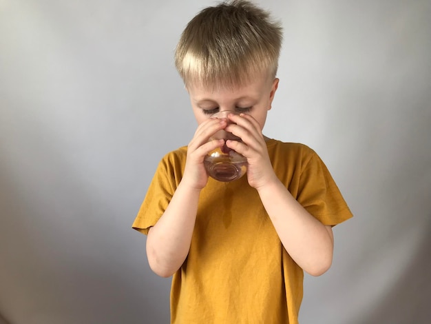 little boy in a yellow Tshirt drinks water