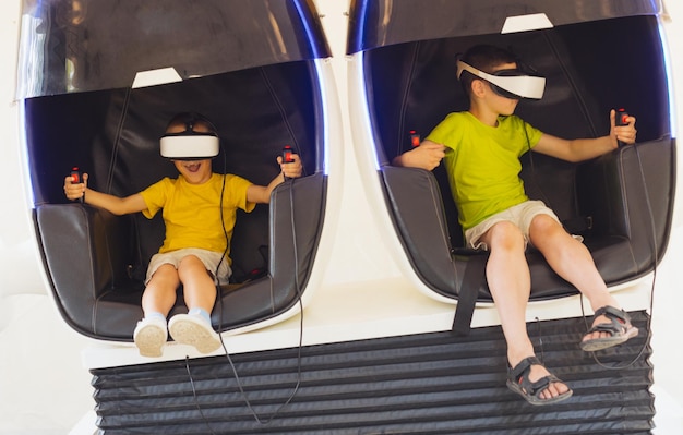 The little boys play the game in virtual reality goggles outdoors