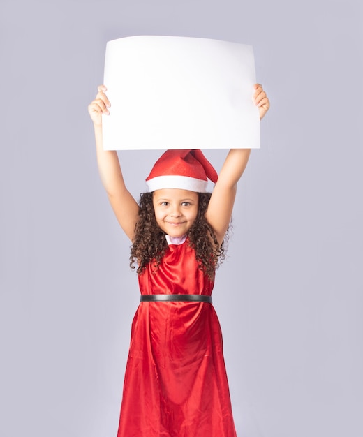 little Brazilian girl dressed with christmas costume holding blank poster