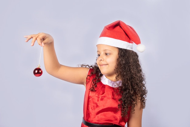 little Brazilian girl dressed with christmas costume holding decoration