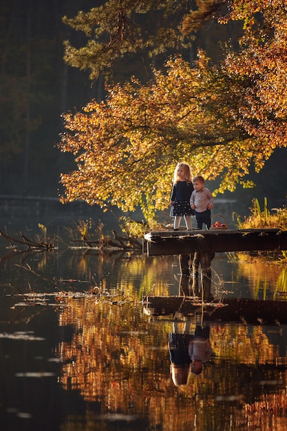 Little brother and sister are playing in the park by the lake.