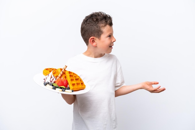 Little caucasian boy holding a waffles isolated on white background with surprise facial expression