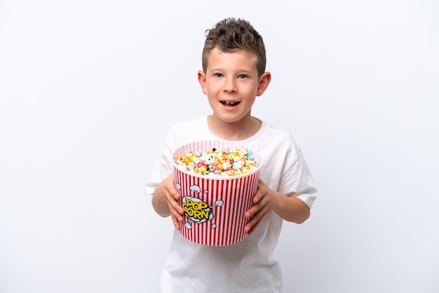 Little caucasian boy isolated on white background holding a big bucket of popcorns