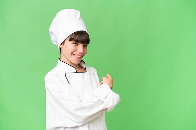 Little caucasian chef girl over isolated background pointing back