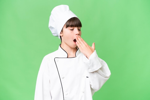 Little caucasian chef girl over isolated background yawning and covering wide open mouth with hand