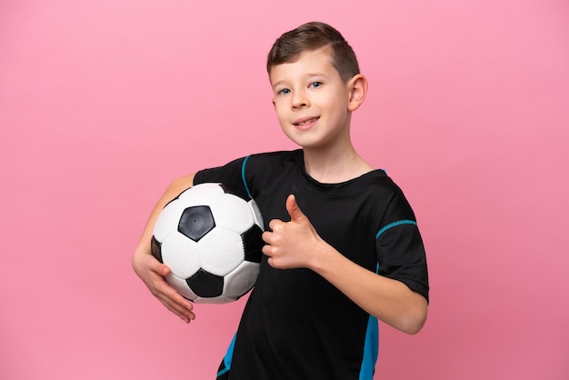 Little caucasian football player boy isolated on pink background giving a thumbs up gesture