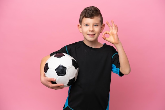 Little caucasian football player boy isolated on pink background showing ok sign with fingers