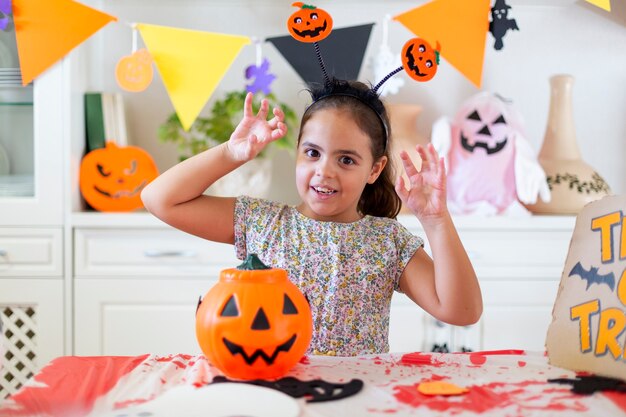 Little caucasian girl having fun time during Halloween party celebration at home.