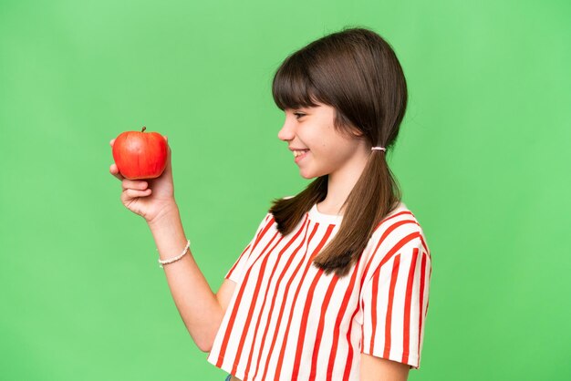 Little caucasian girl holding an apple over isolated background with happy expression