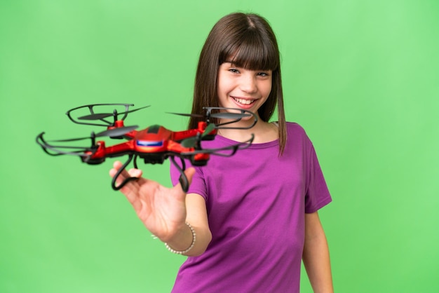 Little caucasian girl holding a drone over isolated background with happy expression