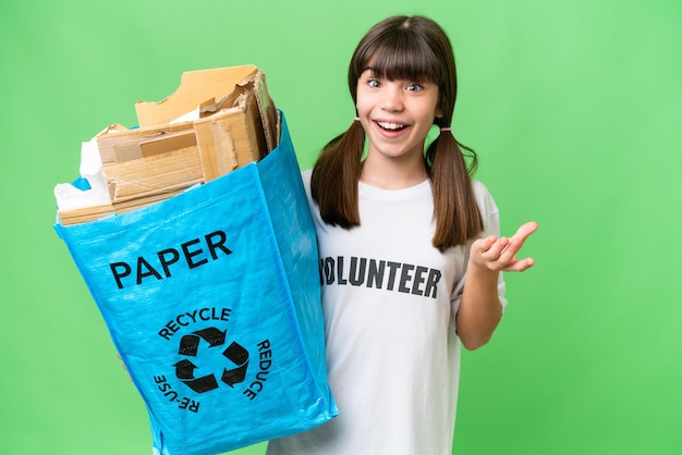 Little Caucasian girl holding a recycling bag full of paper to recycle over isolated background with shocked facial expression