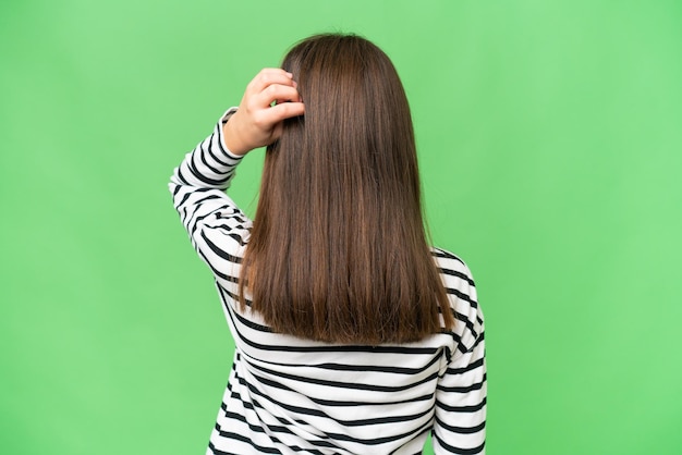 Little caucasian girl over isolated background in back position and thinking