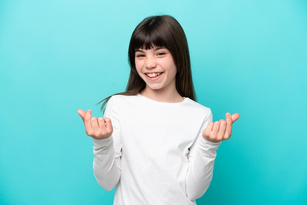 Little caucasian girl isolated on blue background making money gesture