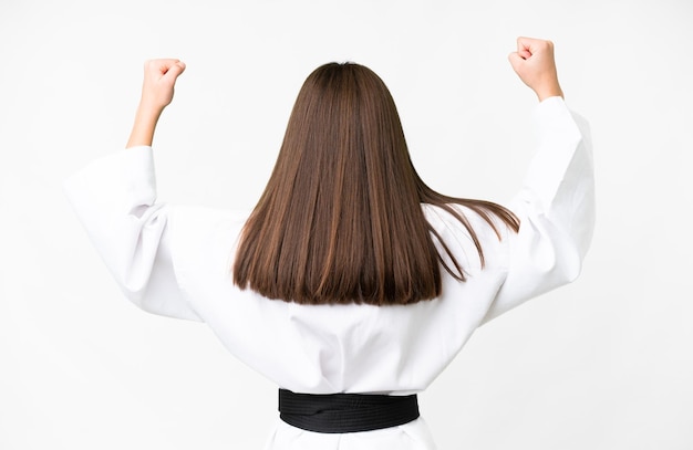 Little caucasian girl over isolated white background doing karate in back position