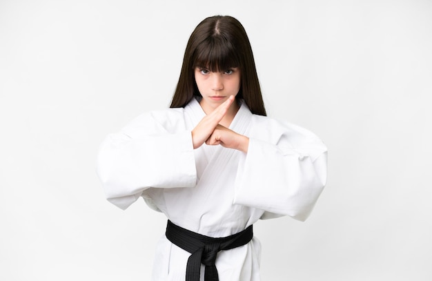 Photo little caucasian girl over isolated white background doing karate and saluting