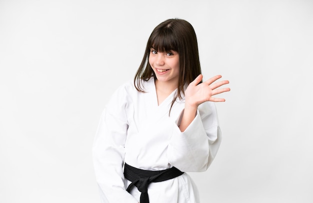 Little caucasian girl over isolated white background saluting with hand with happy expression