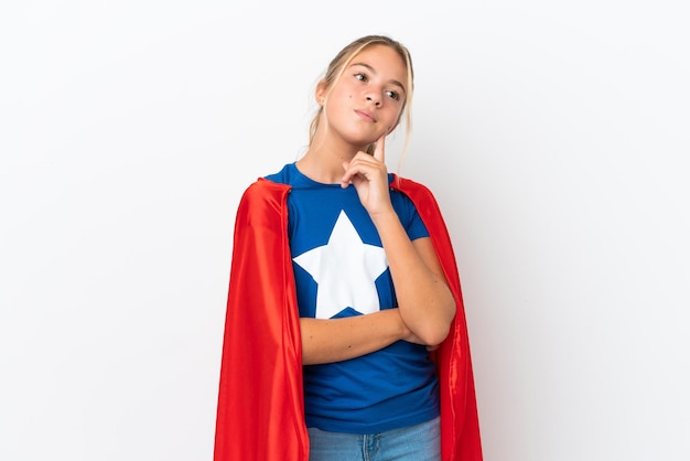 Little caucasian girl isolated on white background in superhero costume and thinking