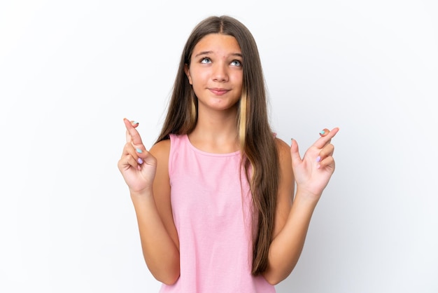 Little caucasian girl isolated on white background with fingers crossing and wishing the best