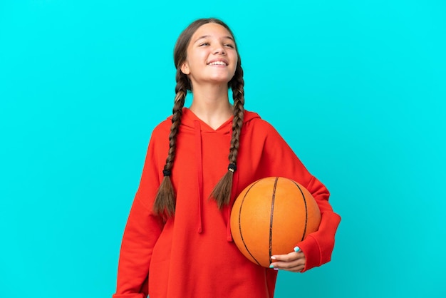 Photo little caucasian girl playing basketball isolated on blue background laughing