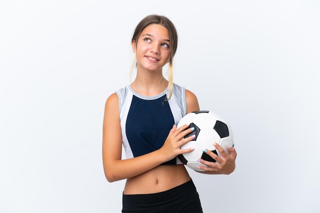 Little caucasian girl playing football isolated on white background thinking an idea while looking up