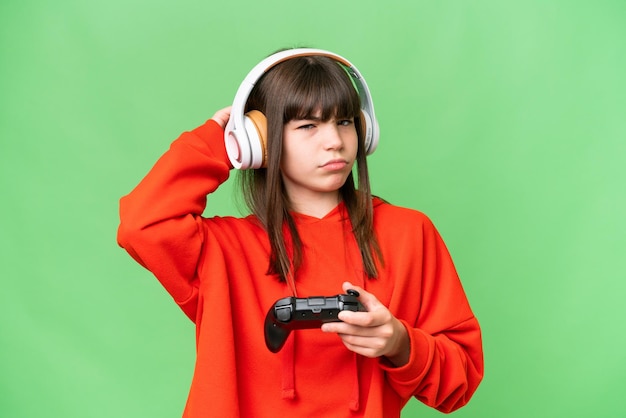 Little caucasian girl playing with a video game controller over isolated background having doubts