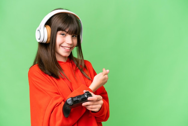 Little caucasian girl playing with a video game controller over isolated background pointing back