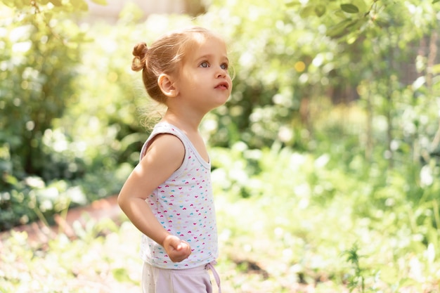 Little Caucasian girl, two years old, gathering unripe cherries in orchard