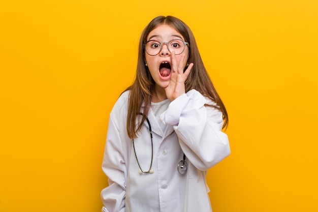 Little caucasian girl wearing a doctor costume shouting excited to front.