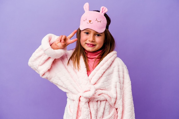 Little caucasian girl wearing pajama isolated on purple wall showing number two with fingers.