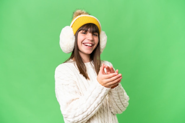 Little caucasian girl wearing winter muffs over isolated background applauding after presentation in a conference