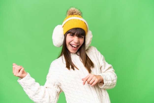 Little caucasian girl wearing winter muffs over isolated background making guitar gesture