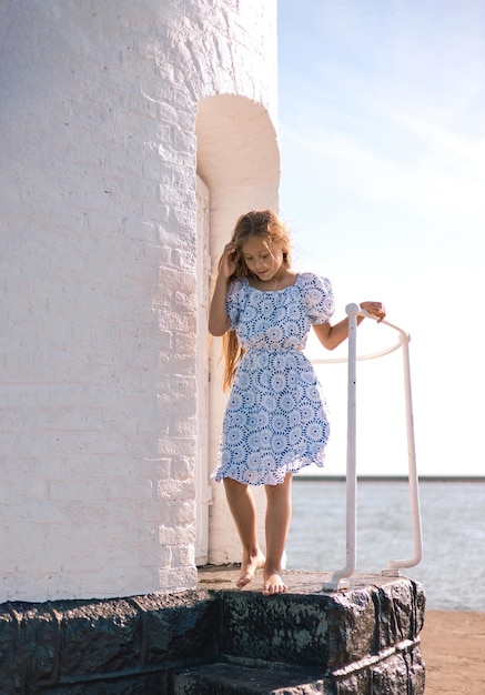 little Caucasian girl in a white dress and long hair walking to the sea Relaxation Childhood