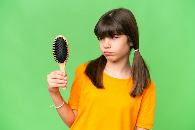 Little caucasian girl with hair comb over isolated background with sad expression