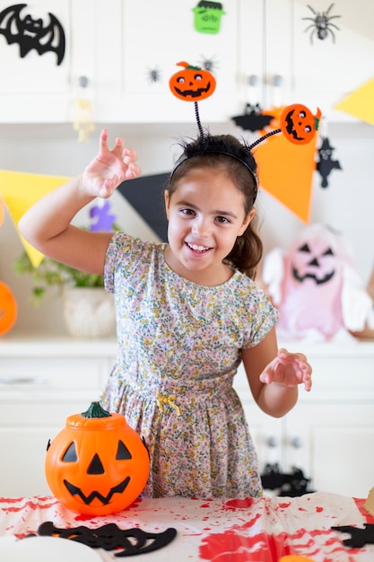 Little caucasian girl with scary pose during halloween party. She is at home.